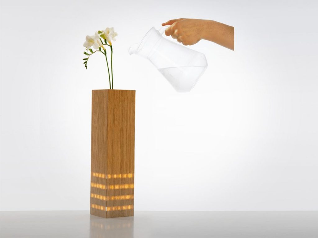 Vase with illuminated stripes behind the wooden veneer